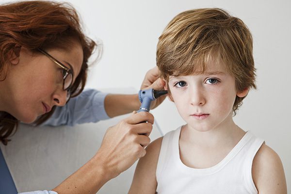 A young boy getting his ears inspected during pediatric hearing assessment at Audiological Services in Lufkin, TX